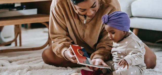 Parent reading a book to their newborn child